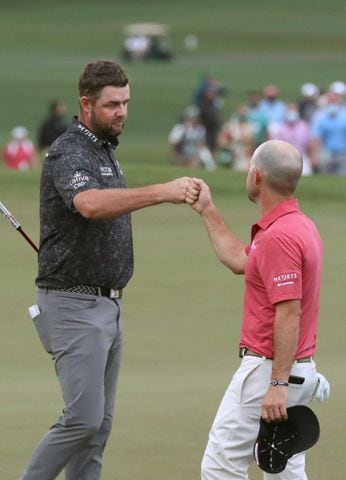 April 10, 2021, Augusta: Marc Leishman and Brian Harman give each other a fist bump as they finish their third round during the Masters at Augusta National Golf Club on Saturday, April 10, 2021, in Augusta. Curtis Compton/ccompton@ajc.com