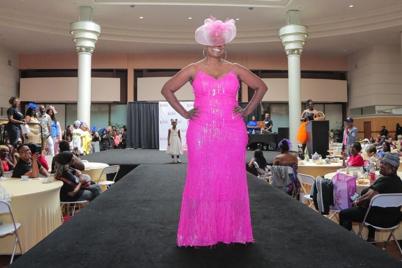 Wearing a bright pink ensemble, a model stops for a photo on the catwalk at 'Seniors on the Runway,' a fashion event held May 4, 2024, at Atlanta's Greenbriar Mall.