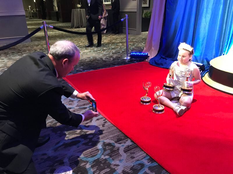  Brendan Keefe takes a shot of his daughter Mackie with a few of his Emmys. CREDIT: Rodney Ho/rho@ajc.com