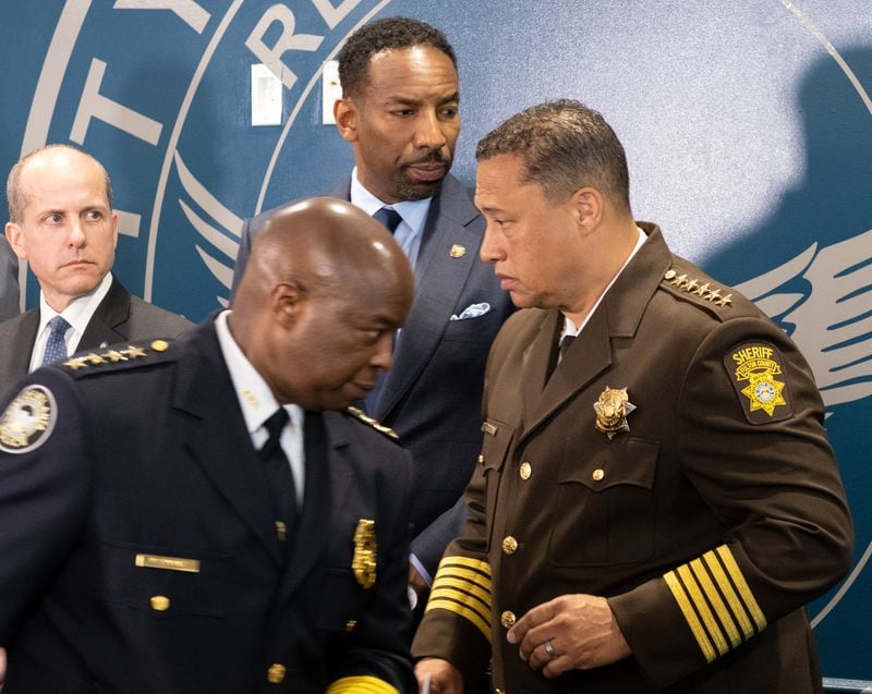 220329-Atlanta-Atlanta Police Chief Rodney Bryant, left and Fulton County Sheriff Pat Labat pass in front of Atlanta Mayor Andre Dickens during a press conference Tuesday, Mar. 29, 2022, to announce the formation of a unit targeting repeat offenders. Ben Gray for the Atlanta Journal-Constitution