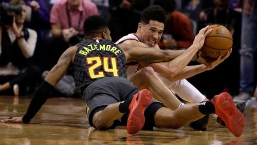 Phoenix Suns guard Devin Booker (1) and Atlanta Hawks guard Kent Bazemore battle for a loose ball Tuesday, Jan. 2, 2018, in Phoenix. The Suns defeated the Hawks 104-103.