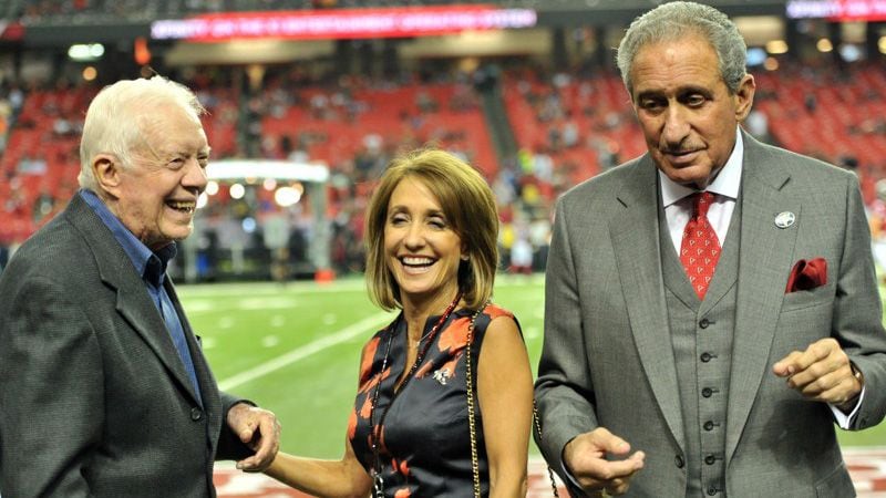 In this September 2014 file photo, former President Jimmy Carter (left) shared a smile with Angie Macuga, who’s now married to Atlanta Falcons owner Arthur Blank (right), before their game against the Tampa Bay Buccaneers.