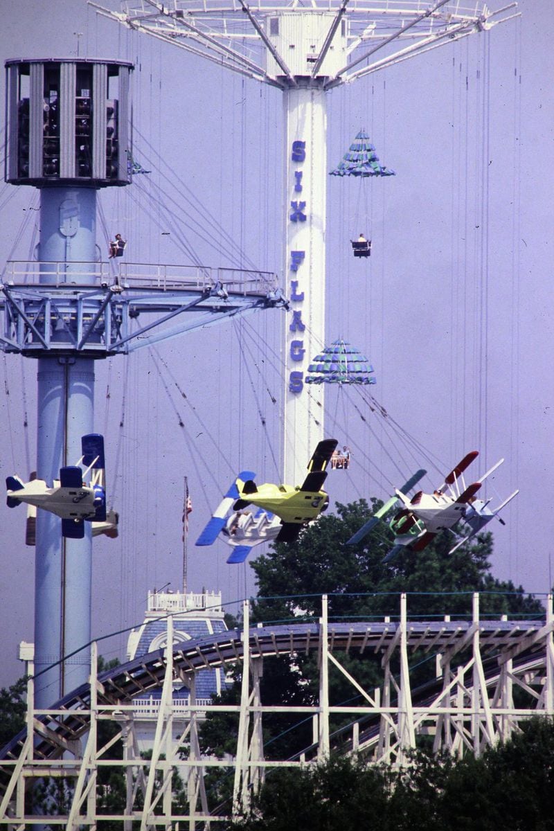 The Great Air Racer airplane ride, the Great Gasp parachute ride (background) and the Georgia Cyclone roller coaster were three popular rides at Six Flags Over Georgia in the 1990s. CONTRIBUTED BY SIX FLAGS OVER GEORGIA