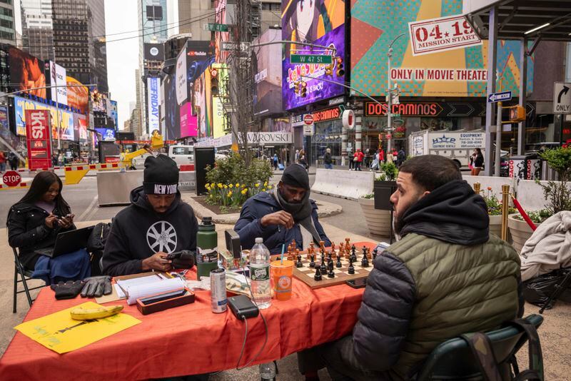 Tunde Onakoya, center, Nigerian chess champion and child education advocate, plays a chess game in Times Square, Friday, April 19, 2024, in New York. (AP Photo/Yuki Iwamura)