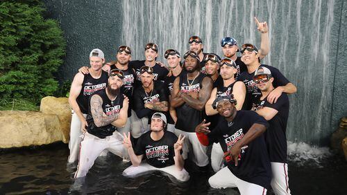 Braves players climb into the outfield waterfall to celebrate clinching the National League East title.  Curtis Compton/ccompton@ajc.com