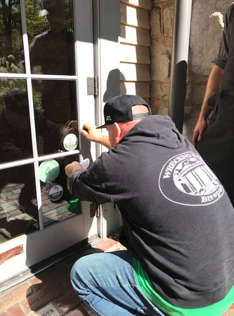 A member of the Wrecking Bar team applies a Farmer Champion decal to the restaurant's door.
