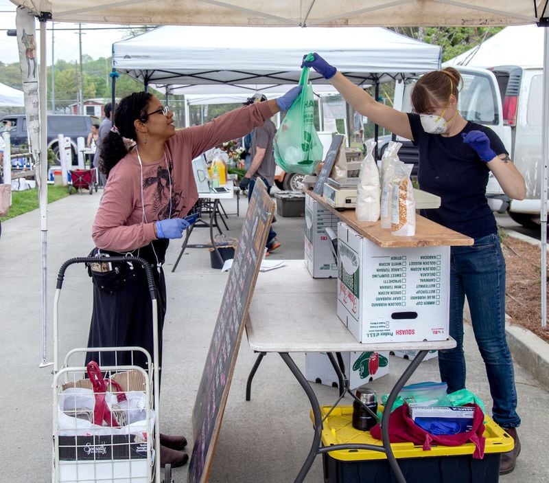 Grant Park Farmers Market’s personal shopper Mercedes Melendez (left) buys groceries for her client on March 29, 2020. STEVE SCHAEFER / SPECIAL TO THE AJC