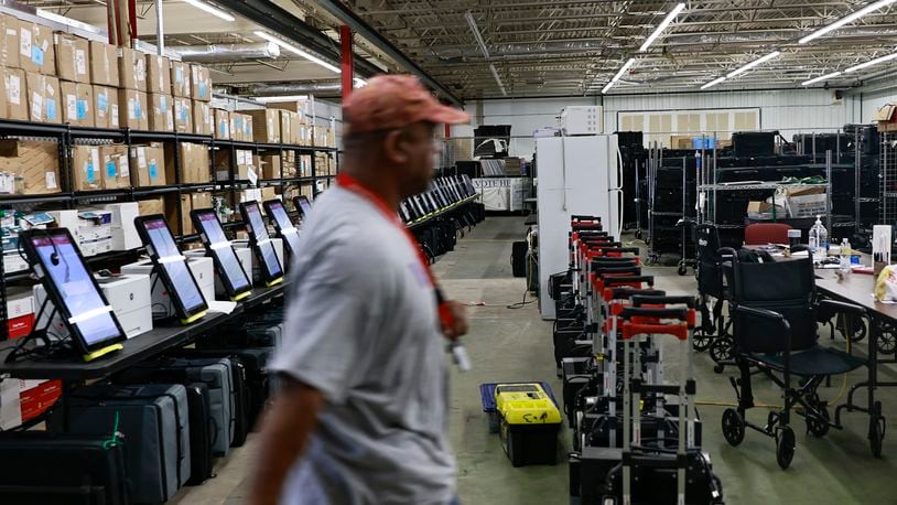An election worker walks past ballot marking devices inside the Clayton County Elections Warehouse on Wednesday.  (Natrice Miller / natrice.miller@ajc.com)