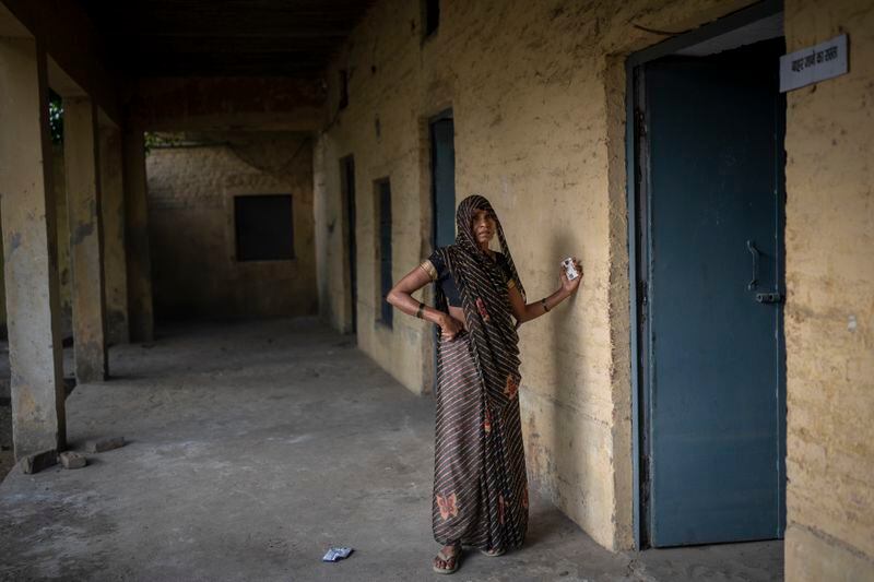 A woman waits at the door of a polling booth to cast her vote during the third round of voting in the six-week-long general election in Agra, Uttar Pradesh, India, Tuesday, May 7, 2024. (AP Photo/Altaf Qadri)