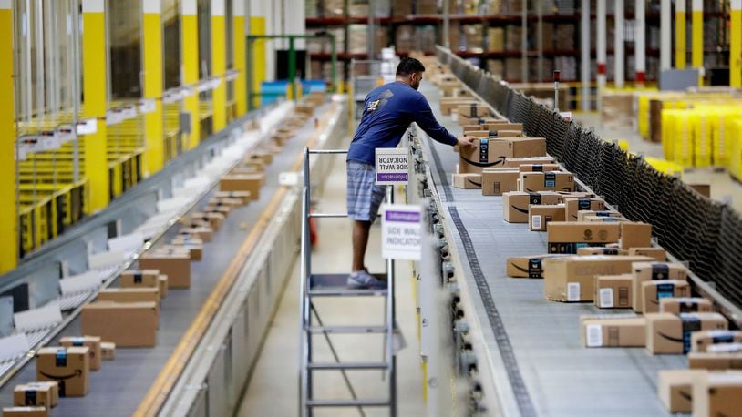 In this 2017 photo, an Amazon employee makes sure a box riding on a belt is not sticking out at an Amazon Fulfillment center. E-commerce is is helping makers of packaging, such as U.S. Corrugated’s plant in Covington, Ga., grow. The plant will be adding more workers this year.