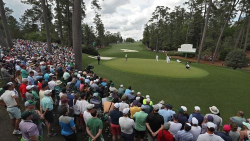A huge gallery congregates around the green on 10 as Tiger Woods putts for a par Friday - a few actually got to see him. (Jason Getz / Special to the AJC)