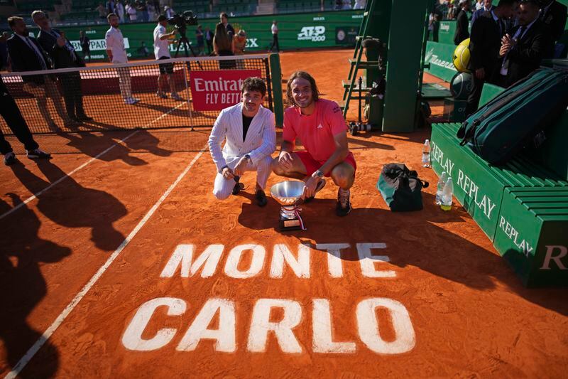Stefanos Tsitsipas of Greece poses with the trophy alongside Ferarri F1 driver Charles Leclerc, left, after defeating Casper Ruud of Norway to win the Monte Carlo Tennis Masters final match 6-1, 6-4 in Monaco, Sunday, April 14, 2024. (AP Photo/Daniel Cole)