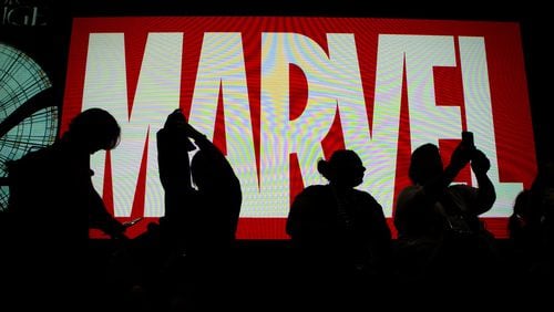 Attendees sit in front of an illuminated Marvel sign during the second day of Comic-Con 2016 in San Diego. This year’s event is July 20-23. Harrison Hill/Los Angeles Times/TNS