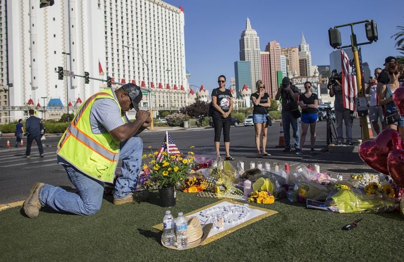 Contractor Robert Walker says a prayer after placing flowers and an American flag last week at the scene of a memorial for the victims of the mass shooting in Las Vegas. GINA FERAZZI / LOS ANGELES TIMES / TNS