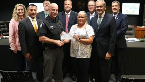 The Sawnee Electric Membership Foundation awards a $7,800 grant to the Johns Creek Public Safety Foundation: (back row) City Council members Stephanie Endres, Jay Lin, Chris Coughlin and John Bradberry; Mayor Mike Bodker; City Council Member Lenny Zaprowski; (front row) Police Chief Ed Densmore; Cindy Badgett, Sawnee EMC; City Council Member Steve Broadbent. CITY OF JOHNS CREEK