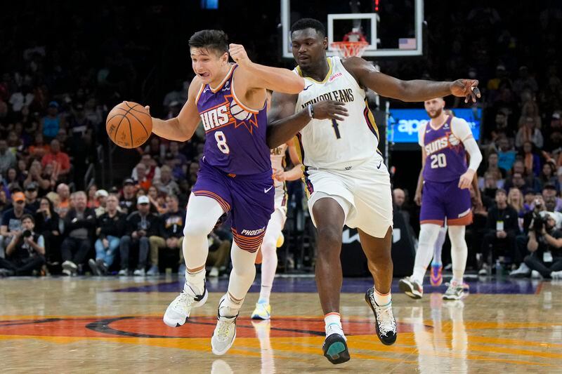 Phoenix Suns guard Grayson Allen (8) shields the ball from New Orleans Pelicans forward Zion Williamson (1) during the second half of an NBA basketball game, Sunday, April 7, 2024, in Phoenix. (AP Photo/Rick Scuteri)