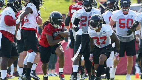 July 27, 2017 Flowery Branch: Falcons running back Devonta Freeman is surrounded by white defensive jersey as he hits a hole for yardage on the first day of team practice at training camp on Thursday, July 27, 2017, in Flowery Branch. Curtis Compton/ccompton@ajc.com