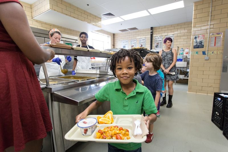 Former kindergartner Isaiah Tillman, now headed to first grade, carries a tray with summer vegetable curry served over brown rice. He’s also got yogurt and orange wedges. Photo: Kelley Klein