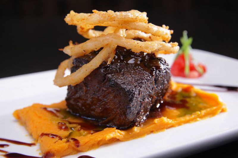  Secreto Southern Kitchen & Bar's bourbon-braised short
								ribs are served on truffle sweet potato puree and topped with
								Cajun shoestring onions.