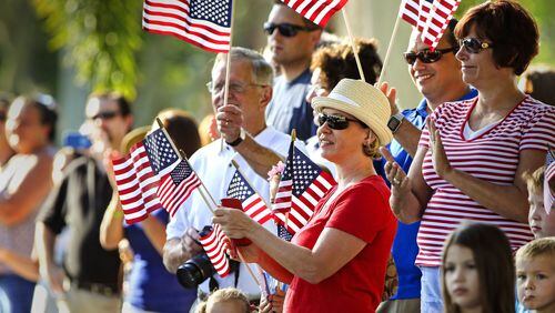 People wave flags during the annual Wellington Memorial Day Parade last year. This year’s parade will commence at Village Hall and make its way to the Wellington Veterans Memorial on Monday morning.LANNIS WATERS / THE PALM BEACH POST