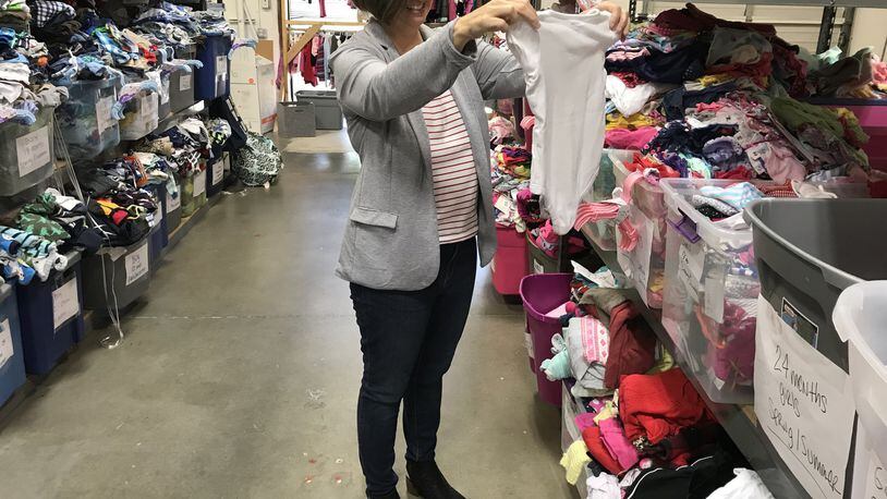 Helping Mamas CEO Jamie Lackey sorts clothing donations at the nonprofit’s Norcross warehouse. CONTRIBUTED