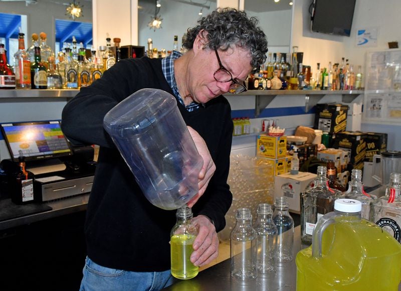 Bill Wood fills to-go bottles of margarita mix for customers at the Cheshire Bridge Road Taqueria del Sol. Chris Hunt for The Atlanta Journal-Constitution 