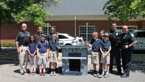 Fifth-grade students at Parkview Christian School in Lilburn pose with the doghouse they made for the Lilburn Police Department’s newest K-9, Ajax.