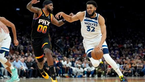 Minnesota Timberwolves center Karl-Anthony Towns (32) drives on Phoenix Suns forward Royce O'Neale during the first half of Game 3 of an NBA basketball first-round playoff series, Friday, April 26, 2024, in Phoenix. (AP Photo/Matt York)