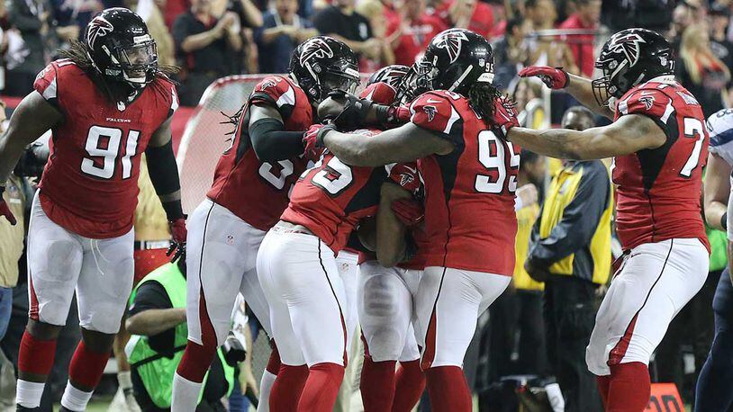 Falcons defenders swarm linebacker Deion Jones after his interception in the final minutes of Saturday's win over the Seahawks.