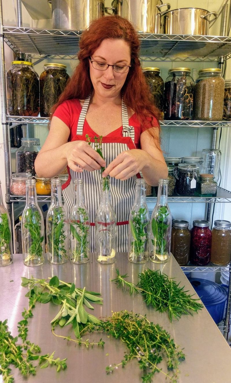  Each bottle of herbal vinegar is made by hand in Piedmont Provisions’ commercial kitchen. Here Heather Russell inserts fresh herbs, like rosemary, sage, and oregano, before adding apple cider vinegar. Photo credit: Piedmont Provisions
