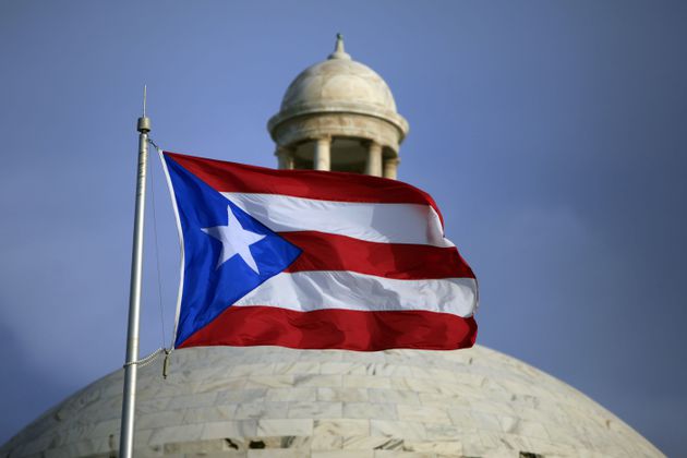 FILE - A Puerto Rican national flag flies in front of the Capitol building in San Juan, Puerto Rico, July 29, 2015. The island’s two biggest political parties hold gubernatorial primaries on Sunday, June 2, 2024. (AP Photo/Ricardo Arduengo, File)