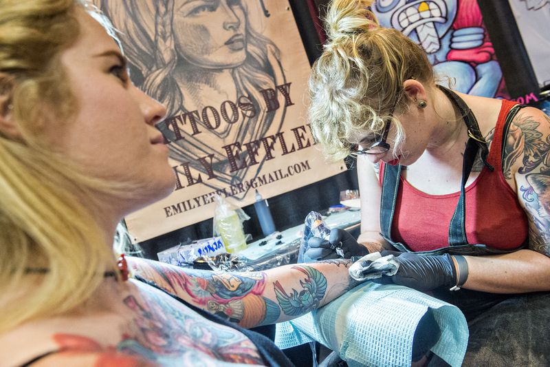 June 20, 2015 Atlanta - Emily Effler (right) works on a wrist tattoo for Glenna Kilgore during the 19th annual Atlanta Tattoo Expo at the Wyndham Atlanta Galleria hotel on Saturday, June 20, 2015. Around 100 tattoo artists from across the country were booked solid throughout the three day event as hundreds of people came out to watch and get tattooed. JONATHAN PHILLIPS / SPECIAL