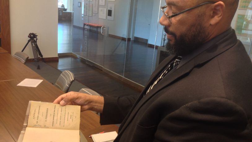 Pellom McDaniels III, a faculty curator of the African American Collections at Emory, marvels at a rare copy of “David Walker’s Appeal” in this AJC file photo. McDaniels died Sunday, April 19, 2020. He was 52.
