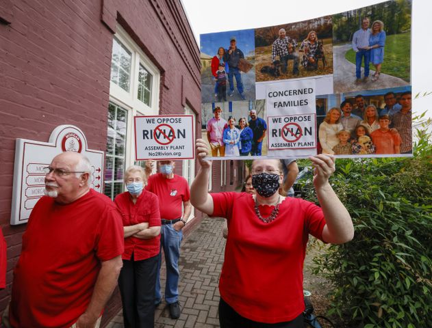 Joanie Fitzgerald (right, with sign), from Rutledge, holds a sign opposing the measure as the group gathered outside after the vote.  The Morgan County board of assessors voted to approve the Rivian tax exemption proposal in Madison on Wednesday, May 25, 2022.   (Bob Andres / robert.andres@ajc.com)