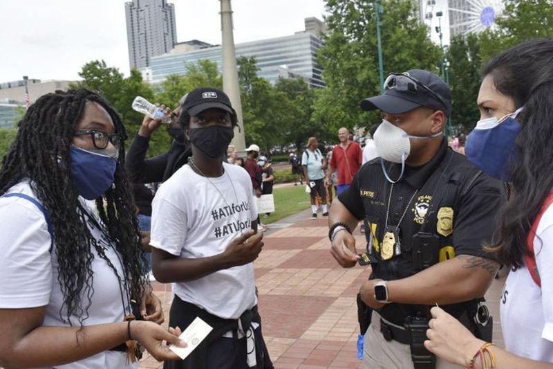19-year-old Zoe Bambara, left, speaks with an Atlanta Police officer in Centennial Olympic Park before the march she organized stepped off. Officers on bikes escorted the protestors to the Gold Dome. ROSS WILLIAMS / GEORGIA RECORDER