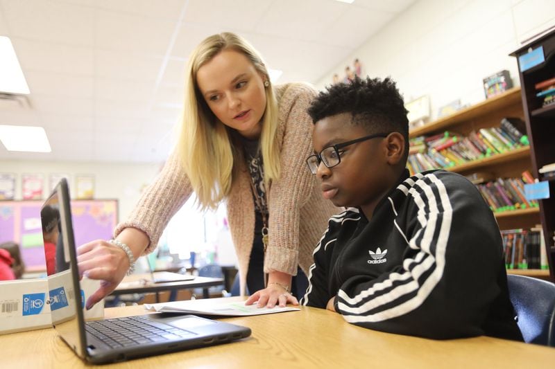 Lauren Pritchard helps eighth grader Tumar Fashola, 13, during a reading class on Friday, Feb. 21, 2020, in Roswell. MIGUEL MARTINEZ FOR THE ATLANTA JOURNAL-CONSTITUTION