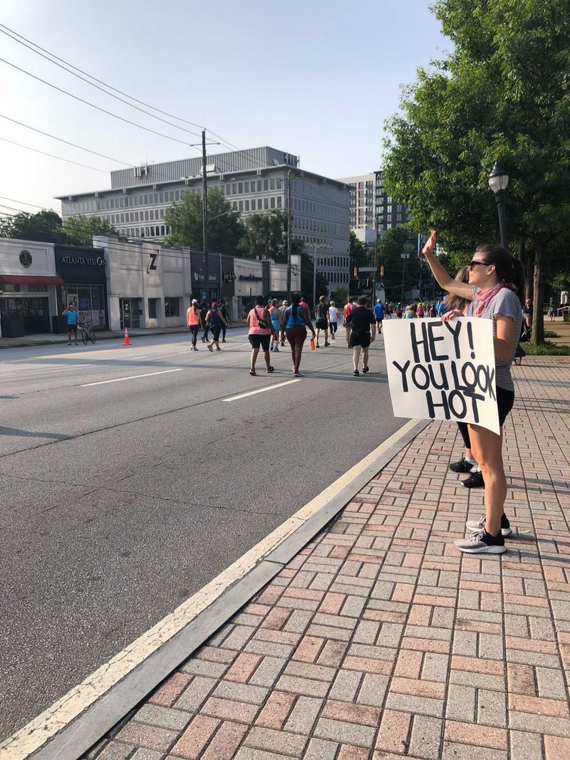 "Hey! You look hot" proclaims the poster for runners passing by Lindsay Cain on Saturday, July 3, 2021, in the Cardiac Hill area. (Photo: Lizzie Kane/AJC)