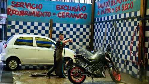 A worker washes a motorcycle at an ecological carwash in Bogota, Colombia, Friday, April 12, 2024. Water rationing in the capital began on Thursday due to the low level of water in reservoirs that give drinking water to the capital, a consequence of the El Niño weather phenomenon. (AP Photo/Fernando Vergara)