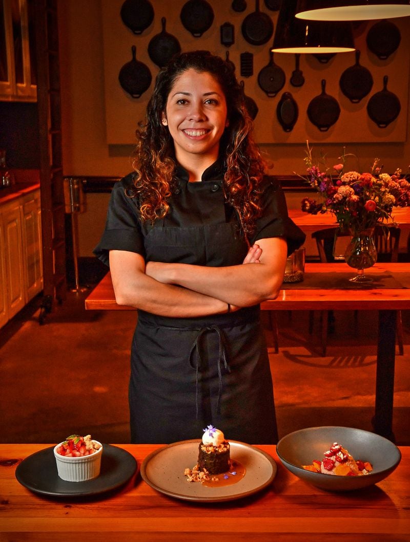 Pastry chef Claudia Martinez of Miller Union, with her desserts: (from left) Meyer Lemon Semifreddo With Oat Cookie Crumble and Macerated Strawberries, Gluten-Free Chocolate Cake With Salted Caramel and Candied Hazelnuts, and Raspberry Cheesecake Mousse With Pretzel Crunch. (Styling by Claudia Martinez / Chris Hunt for the AJC)