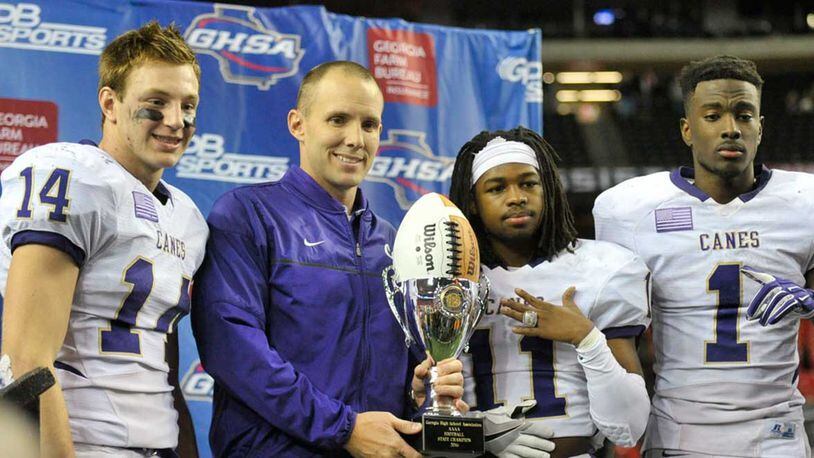 Seniors Sean Holton (14, L-R), Xavior Coaxum (11), Trey Creamer (1) hold their championship trophy with Cartersville head coach Joey King after winning the Class AAAA state title game at the Georgia Dome Saturday.