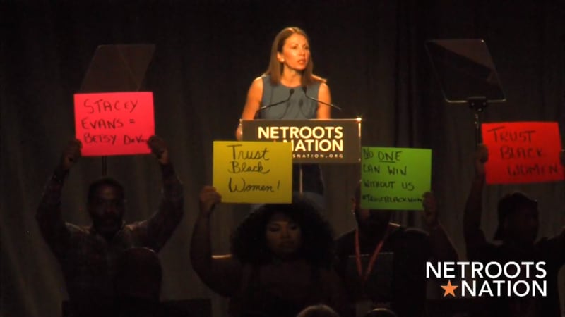 Stacey Evans is drowned out by protesters chanting "support black women" and "trust black women" at the Netroots Nation conference. Screen shot.