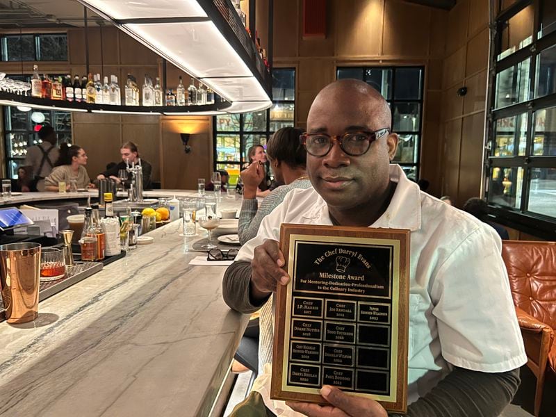Chef Charlie Hatney holds a plaque commemorating winners of the Chef Darryl Evans Milestone Award, which he created and has awarded to chefs annually since 2017.