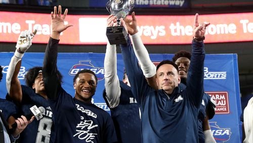 Marietta head coach Richard Morgan hoists the trophy with players after their 17-9 win against Lowndes in the Class AAAAAAA high school football state title at Georgia State Stadium Saturday, December 14, 2019 in Atlanta. (JASON GETZ/SPECIAL TO THE AJC)