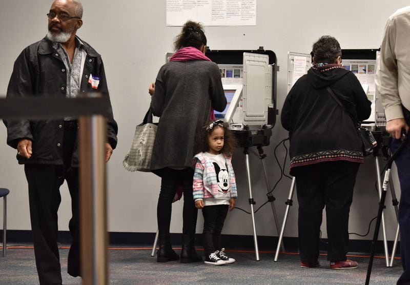 Drina Ramos (center) casts her ballot  as her 3-year-old daughter Talon, 3, waits during early voting at The Gwinnett County Voter Registrations and Elections Office in Lawrenceville on Thursday, October 18, 2018. 