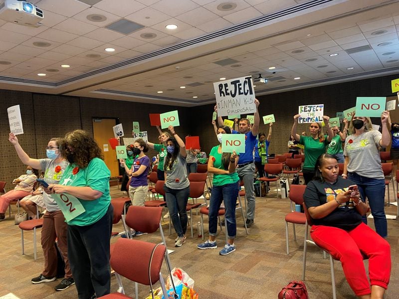 Parents opposed to an Atlanta Public Schools' recommendation to rezone Midtown-area schools hold up signs during a Monday, May 2, 2022, board meeting. VANESSA McCRAY/AJC