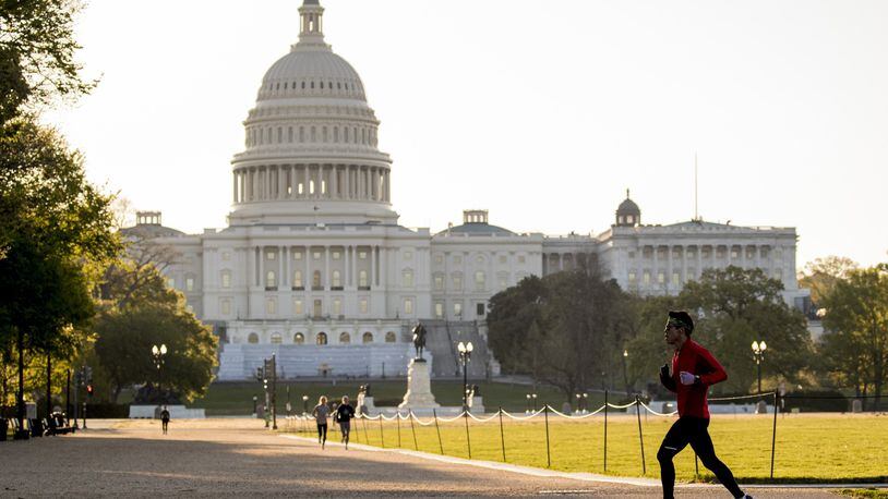The U.S. Capitol Building is visible as a jogger makes their way across the National Mall, Wednesday, April 22, 2020, in Washington. (AP Photo/Andrew Harnik)