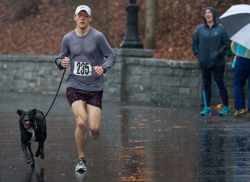 Thomas Clarke and his dog Finn are the first team to cross the finish line during the Piedmont Park Conservancy's 5th Year Anniversary of the Doggie Dash and 5K in Piedmont Park on Sunday, March  11, 2018. Heavy rain continued through the morning.   STEVE SCHAEFER / SPECIAL TO THE AJC