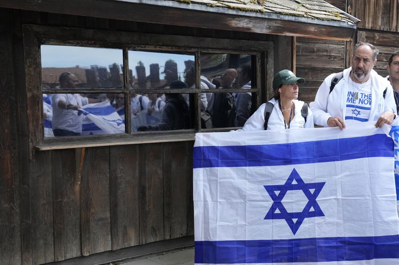 People holding an Israeli flag pose for a photo at the former Nazi German death camp of Auschwitz-Birkenau in Oswiecim, Poland, Monday, May 6, 2024 during the annual Holocaust remembrance event, the "March of the Living" in memory of the six million Holocaust victims. (AP Photo/Czarek Sokolowski)