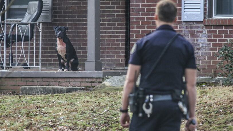 An Atlanta police office corners one of the dogs on Thurgood Street. JOHN SPINK /JSPINK@AJC.COM