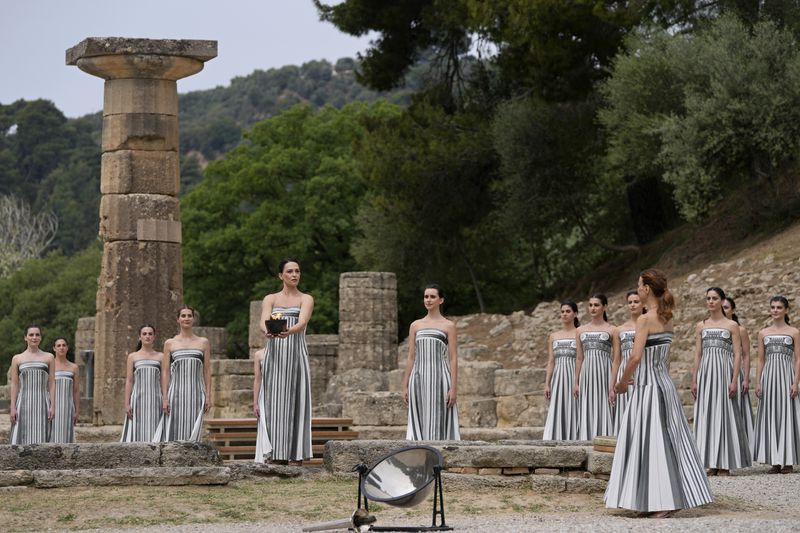 Actress Mary Mina, playing high priestess, holds a ceramic pot with a flame lit the day before during the official ceremony of the flame lighting for the Paris Olympics, at the Ancient Olympia site, Greece, Tuesday, April 16, 2024. The flame will be carried through Greece for 11 days before being handed over to Paris organizers on April 26. (AP Photo/Thanassis Stavrakis)